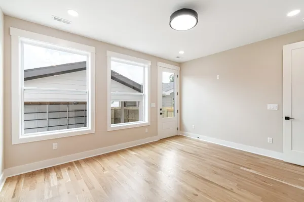 an empty room with wooden floor and windows