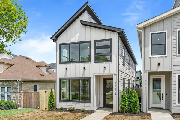 a view of a white house with a small yard and potted plants