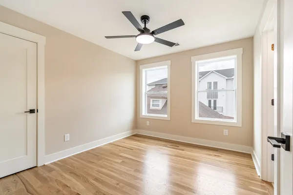 an empty room with wooden floor and windows