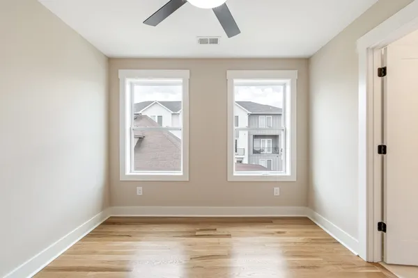 a view of an empty room with a window and wooden floor