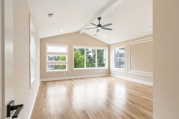 a view of an empty room with a window and wooden floor