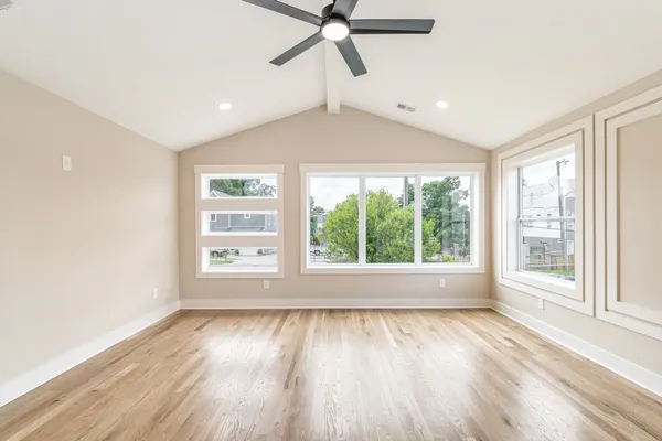 a view of an empty room with wooden floor and a window