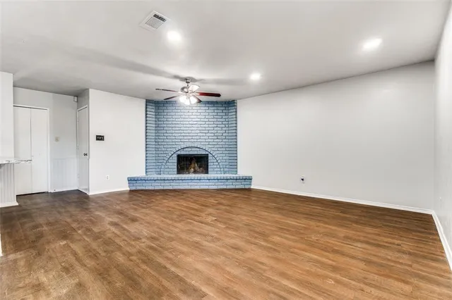 a view of an empty room with wooden floor and a fireplace