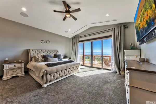 a spacious bedroom with a bed a couch and a flat tv screen