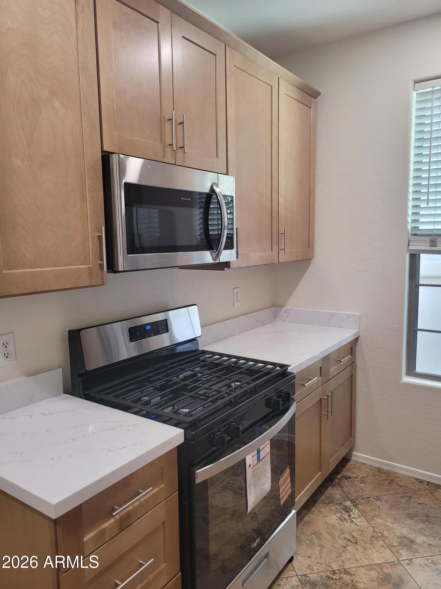 1453 South Sinova Avenue Gilbert, AZ 85296 - Photo 5 of 46 a kitchen with stainless steel appliances a stove a microwave and cabinets