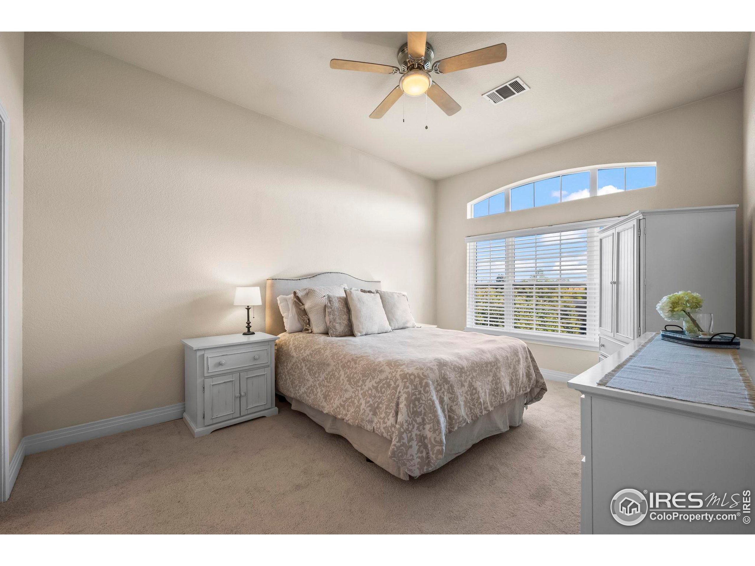 209 Quebec Street, Unit L Denver, CO 80220 - Photo 20 of 46 a spacious bedroom with a bed a window and a chandelier