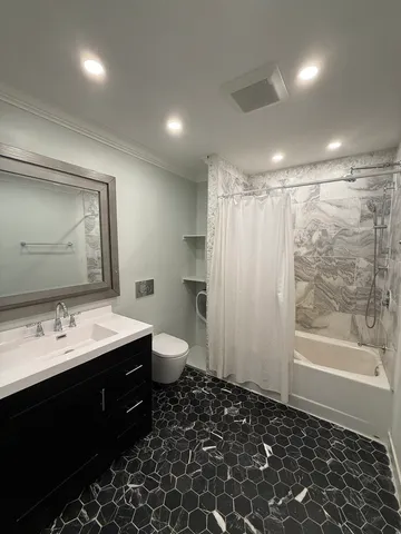 a bathroom with a bathtub shower sink mirror and toilet