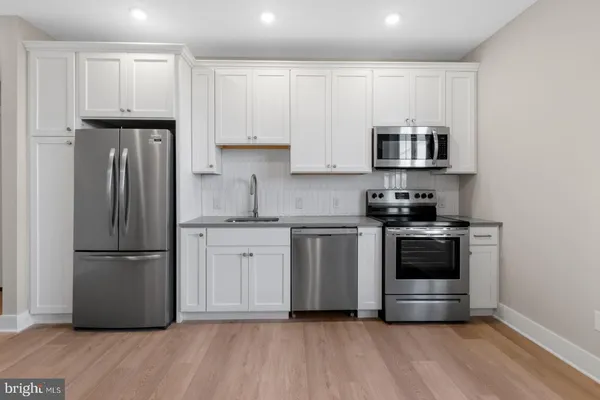 a kitchen with stainless steel appliances granite countertop a refrigerator stove a sink and white cabinets