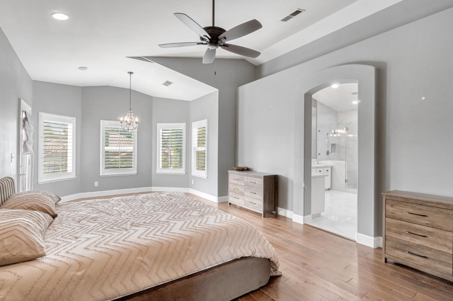 12 Breeze Way Madera, CA 93637 - Photo 39 of 56 a spacious bedroom with a large bed a chandelier and a window