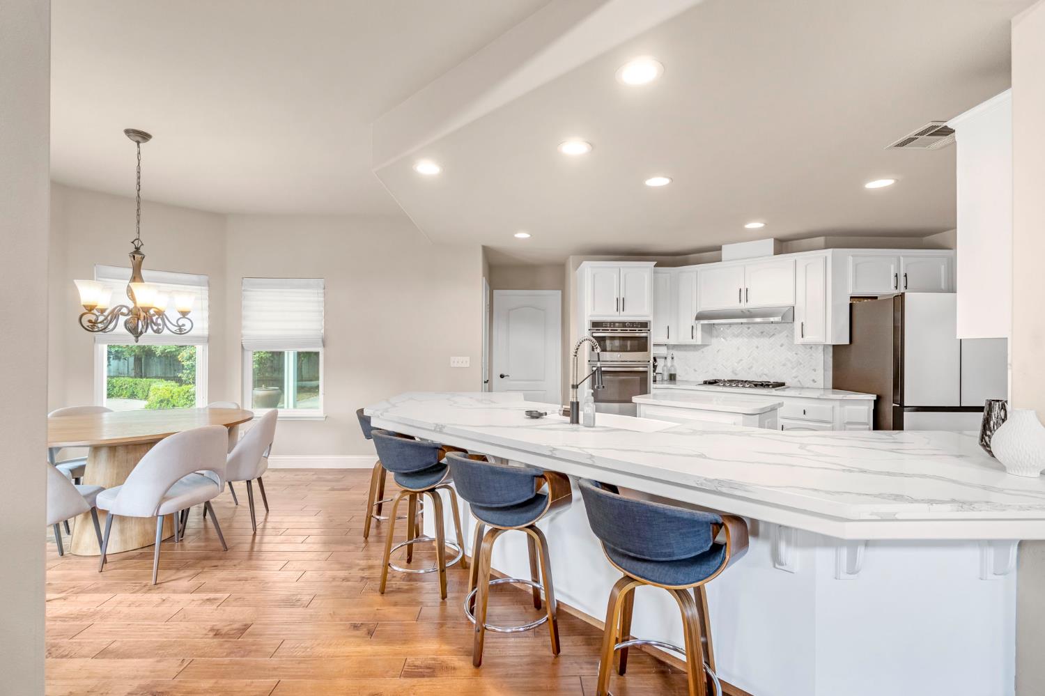 12 Breeze Way Madera, CA 93637 - Photo 10 of 56 a kitchen with stainless steel appliances kitchen island granite countertop a dining table chairs and white cabinets