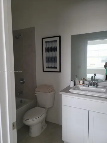 a bathroom with a toilet sink vanity granite and a shower