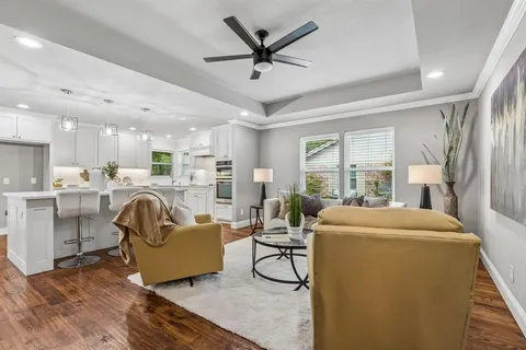 a living room with furniture a ceiling fan and a large window