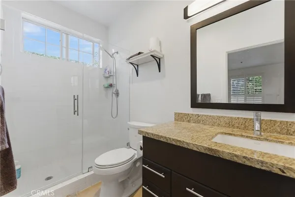 a bathroom with a granite countertop sink toilet and shower