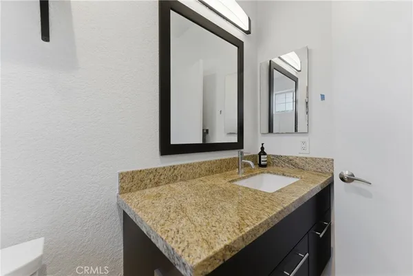 a bathroom with a granite countertop sink and a mirror