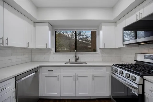 a kitchen with white cabinets and appliances
