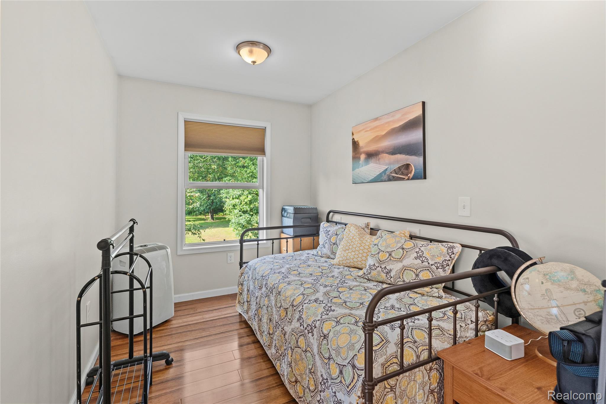 15055 South Duffield Road Byron, MI 48418 - Photo 25 of 61 Bright room featuring a window with a roller shade, wood-finish flooring, and a flush-mount ceiling light fixture