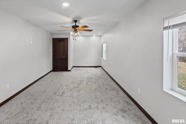 en empty room with windows and ceiling fan