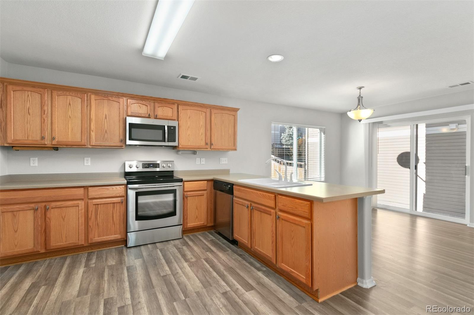 2562 Coach House Loop Castle Rock, CO 80109 - Photo 7 of 20 a kitchen with stainless steel appliances granite countertop a stove top oven a sink dishwasher and a refrigerator with wooden floor