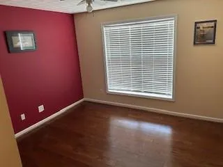 a view of an empty room with a window and wooden floor