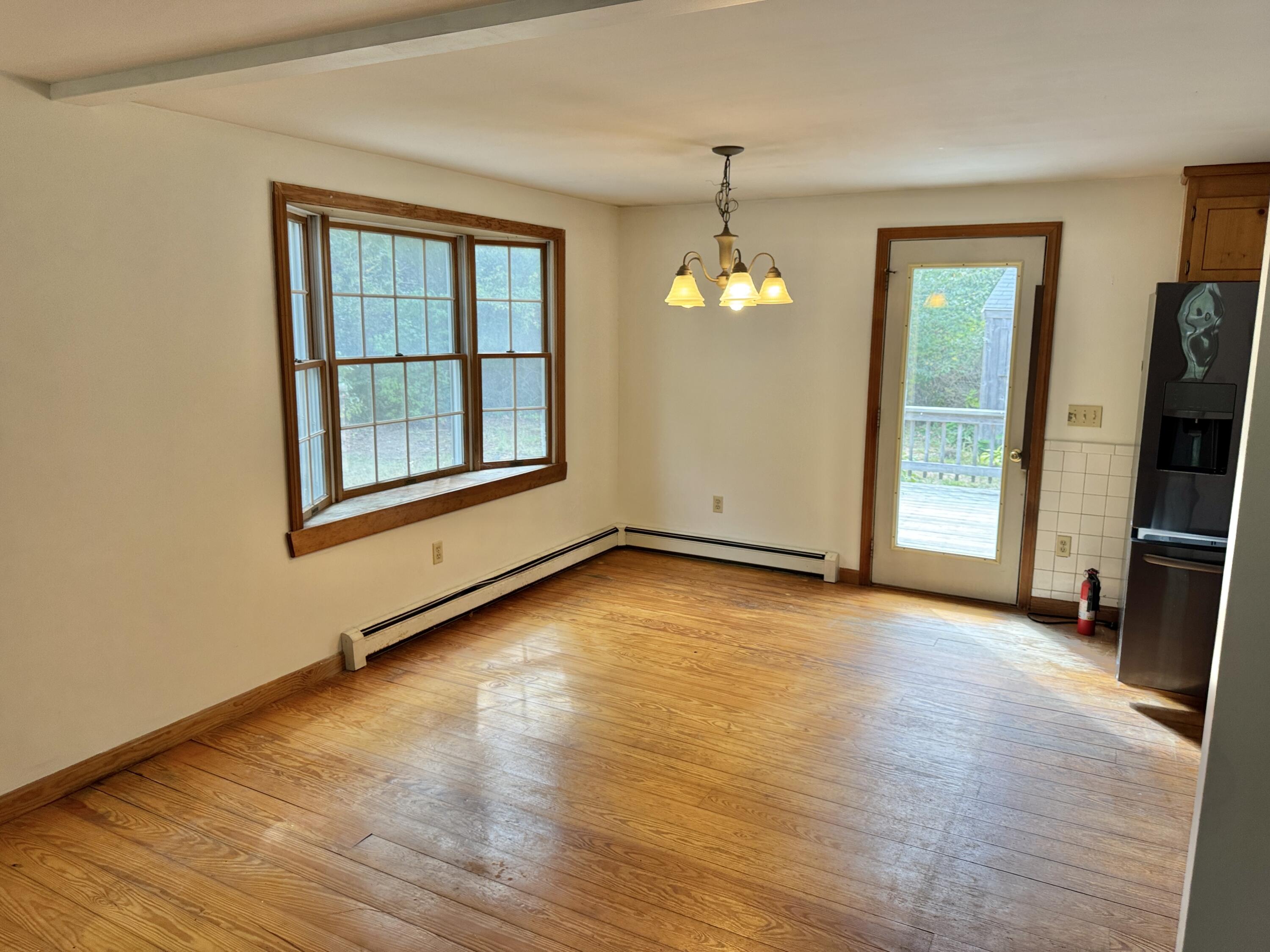 255 Massasoit Road Eastham, MA 02642 - Photo 11 of 25 an empty room with wooden floor mirror and windows
