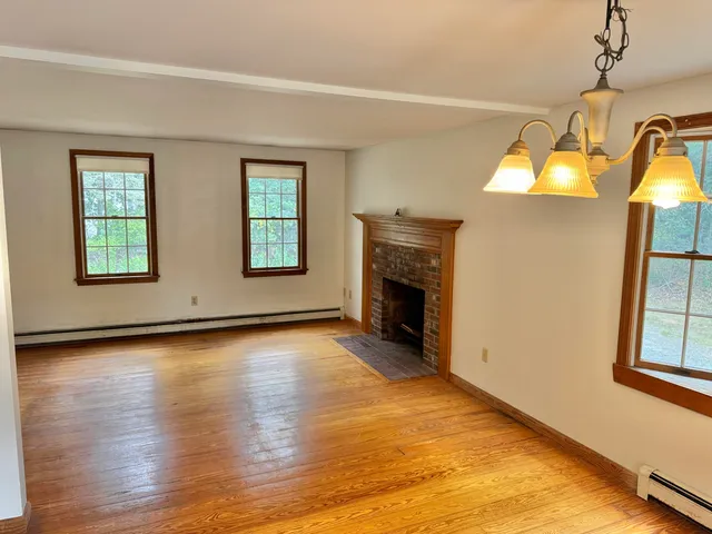 a view of an empty room with window and wooden floor