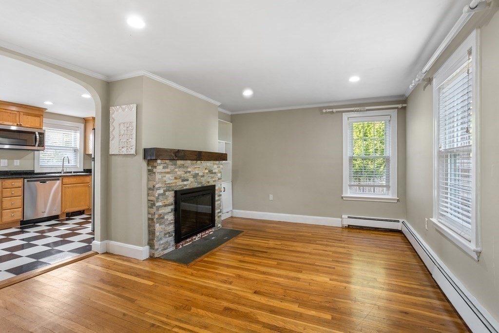 140 Lowell Street Lexington, MA 02420 - Photo 8 of 37 an empty room with wooden floor fireplace and windows