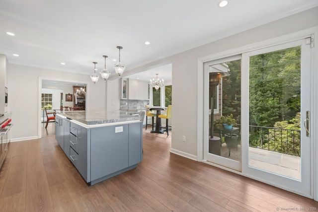 a large open kitchen with kitchen island wooden floor and large window