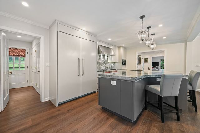 a kitchen with kitchen island granite countertop a sink cabinets and wooden floor