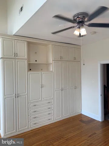 an empty room with wooden floor cabinet and a ceiling fan