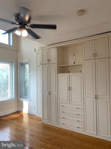 a view of empty room with wooden floor and fan