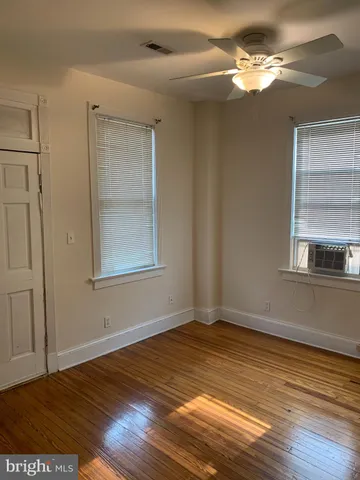a view of empty room with wooden floor and fan