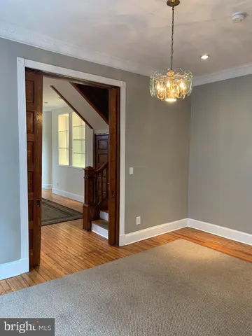 a view of a livingroom with a chandelier curtains and wooden floor