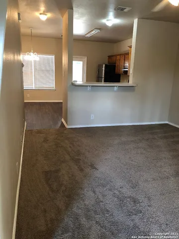 a view of a hallway with wooden floor and a kitchen