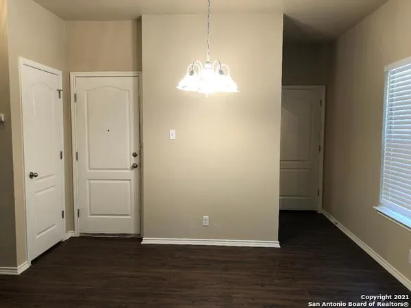 an empty room with wooden floor cabinet and windows