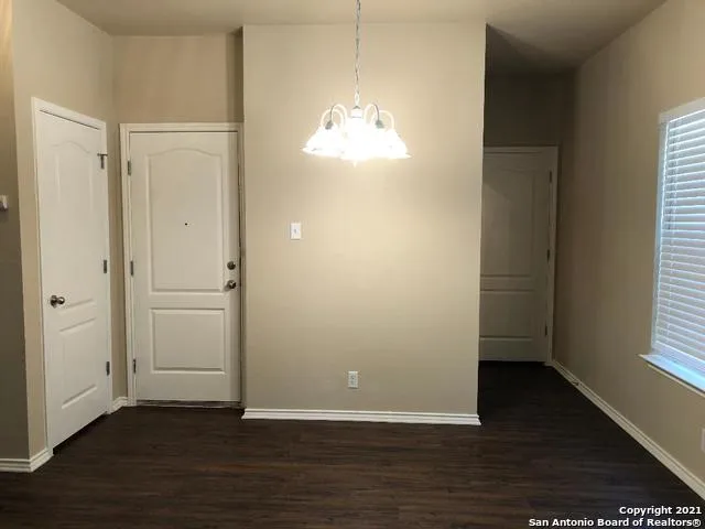 an empty room with wooden floor cabinet and windows