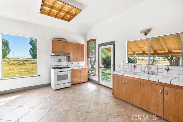 a large kitchen with stainless steel appliances a stove a sink and a large window