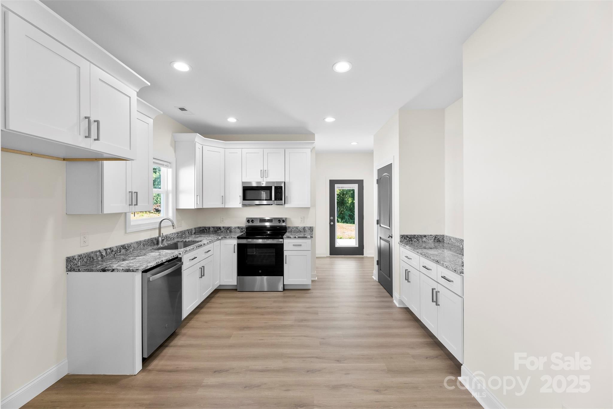 215 Benfield Road Kings Mountain, NC 28086 - Photo 11 of 25 a large kitchen with stainless steel appliances granite countertop a stove top oven a sink dishwasher and a refrigerator with wooden floor