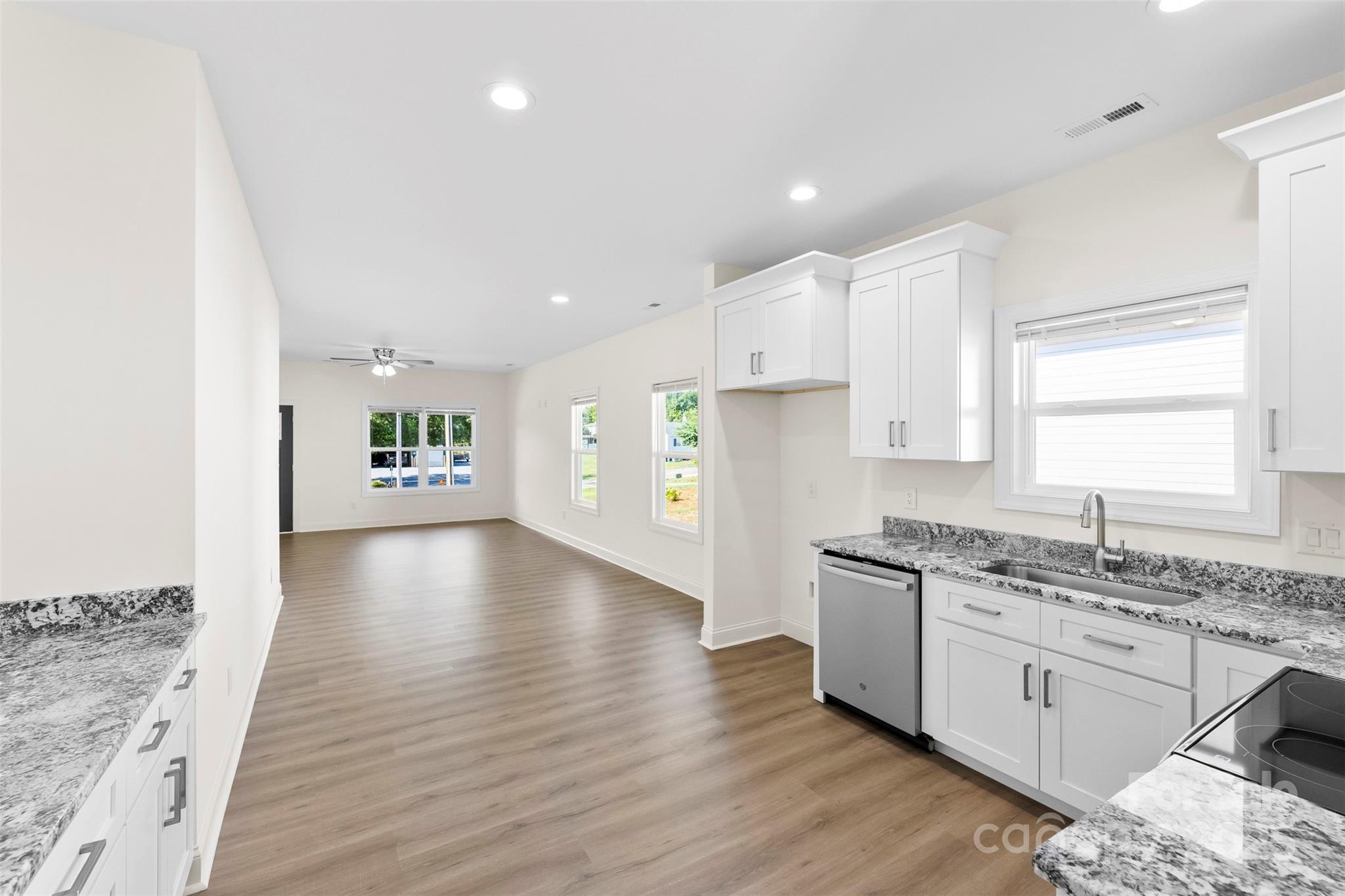 215 Benfield Road Kings Mountain, NC 28086 - Photo 13 of 25 a kitchen with granite countertop a stove a sink and white cabinets with wooden floor
