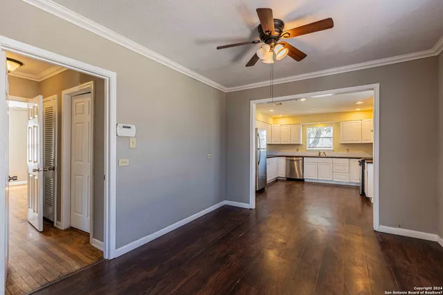an empty room with wooden floor and a ceiling fan