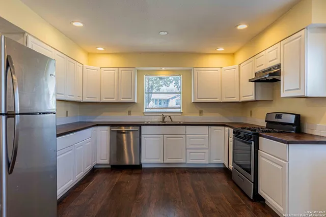 a kitchen with granite countertop white cabinets and wooden floor
