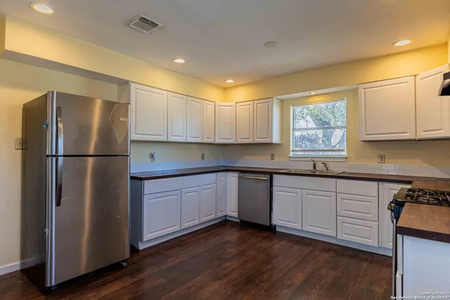a kitchen with granite countertop stainless steel appliances a refrigerator a sink and cabinets