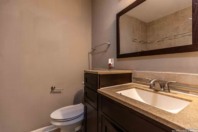 a bathroom with a granite countertop toilet sink and mirror