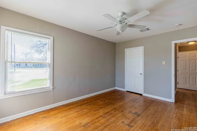 a view of an empty room with wooden floor and a window