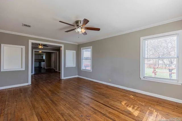 a view of empty room with wooden floor and fan
