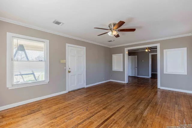 a view of an empty room with window and wooden floor