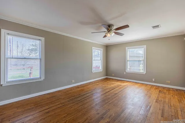 a view of an empty room with a window and wooden floor