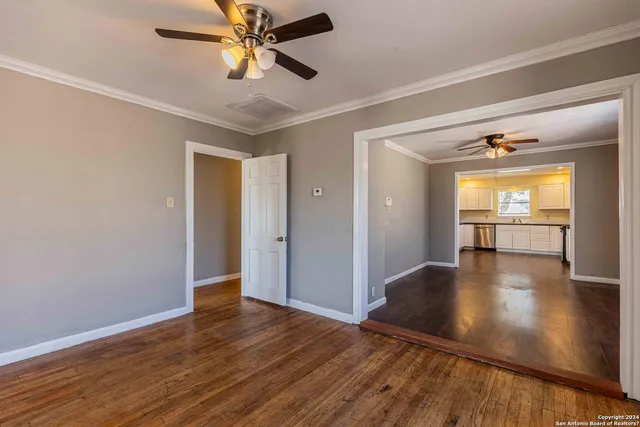 a view of empty room with wooden floor and ceiling fan