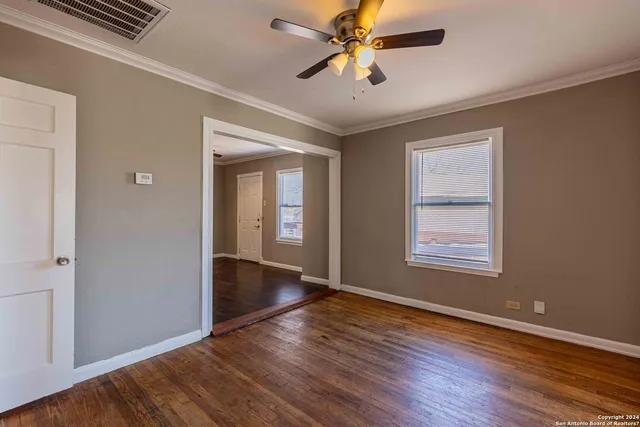 a view of an empty room with wooden floor and a window