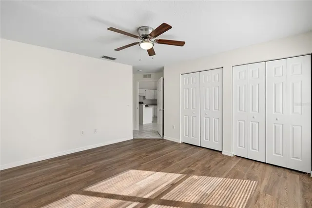 a view of empty room with wooden floor and fan