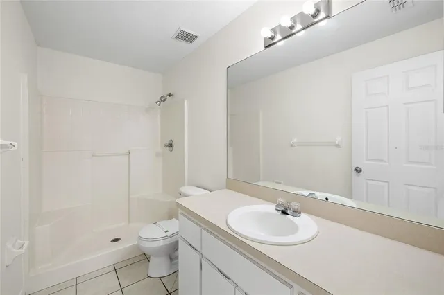 a bathroom with a toilet a sink a mirror and shower